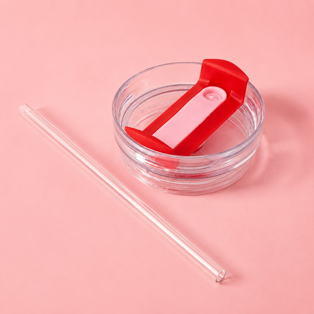 Clear drinking container with red lid and straw on a pink background